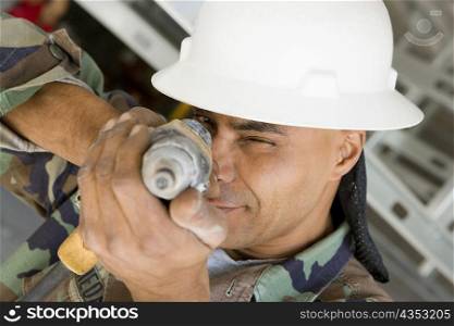 Close-up of a male construction worker aiming with a hand drill