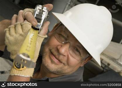 Close-up of a male construction worker holding a tape measure