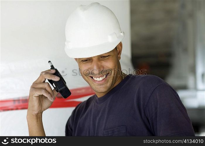 Close-up of a male construction worker talking on a walkie-talkie and smiling