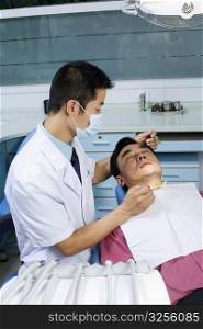 Close-up of a male dentist examining a male patient