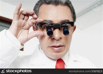 Close-up of a male doctor adjusting lupa binoculars