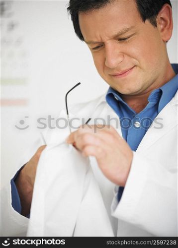 Close-up of a male doctor cleaning his eyeglasses