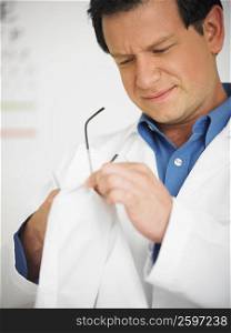 Close-up of a male doctor cleaning his eyeglasses