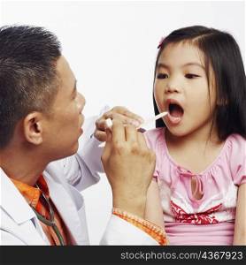 Close-up of a male doctor examining his patient with a tongue depressor