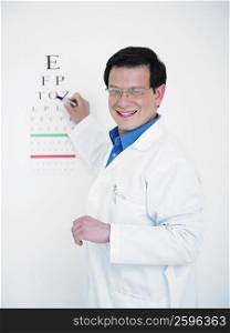 Close-up of a male doctor pointing towards an eye chart