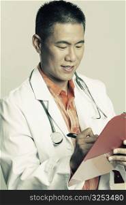 Close-up of a male doctor writing on a clipboard and smiling
