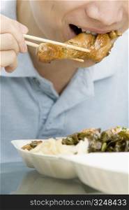 Close-up of a male office worker eating meat with chopsticks