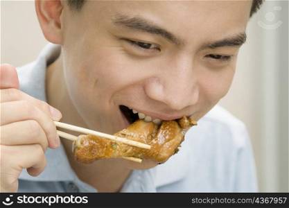 Close-up of a male office worker eating meat with chopsticks