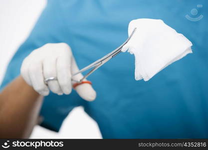 Close-up of a male surgeon&acute;s hand holding a bandage with a pair of surgical scissors
