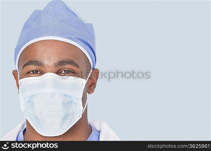 Close-up of a male surgeon wearing mask over light blue background