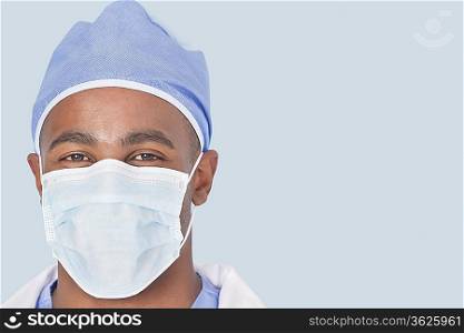 Close-up of a male surgeon wearing mask over light blue background