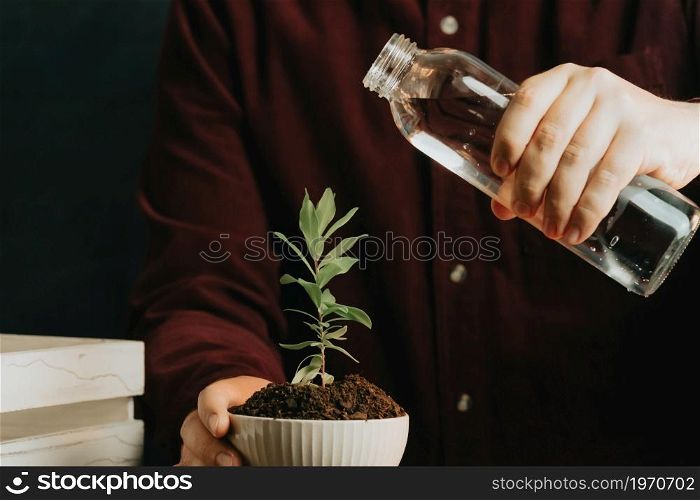 Close up of a man about to water a plant in a pot with copy space