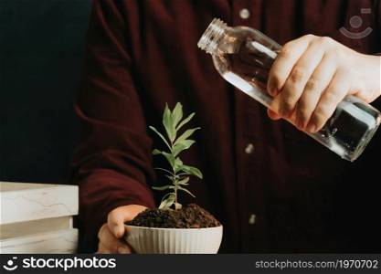 Close up of a man about to water a plant in a pot with copy space