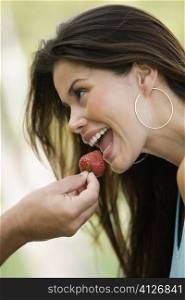 Close-up of a man&acute;s hand feeding a young woman a strawberry