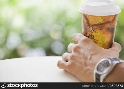 Close-up of a man&acute;s hand holding a disposable cup
