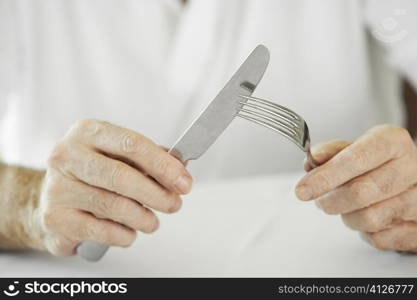 Close-up of a man&acute;s hand holding a table knife and a fork