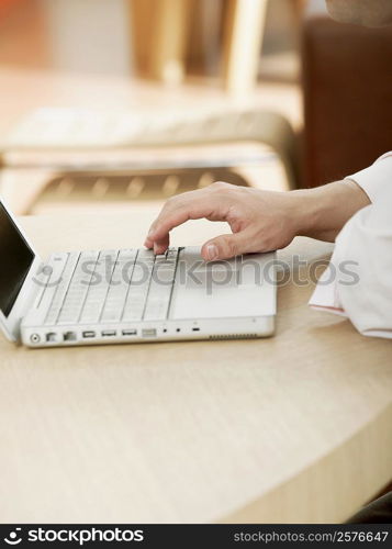 Close-up of a man&acute;s hand operating a laptop