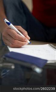 Close-up of a man&acute;s hand writing on a spiral notebook