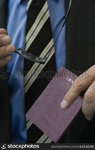 Close-up of a man&acute;s hands holding a passport and eyeglasses