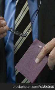 Close-up of a man&acute;s hands holding a passport and eyeglasses