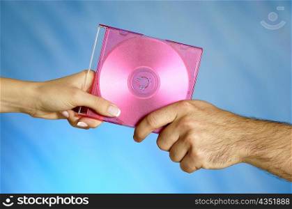 Close-up of a man and a woman&acute;s hands holding a compact disk