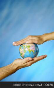 Close-up of a man and a woman&acute;s hands holding a globe