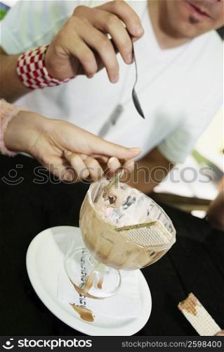 Close-up of a man and a woman sharing an ice-cream sundae