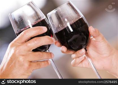Close-up of a man and a woman toasting glasses of red wine