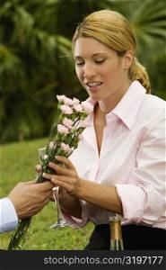 Close-up of a man giving a bunch of flowers to a businesswoman