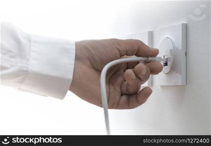Close-up of a man hand plugging an ethernet cable into a wall socket, horizontal image. Concept of broadband network . Company Network