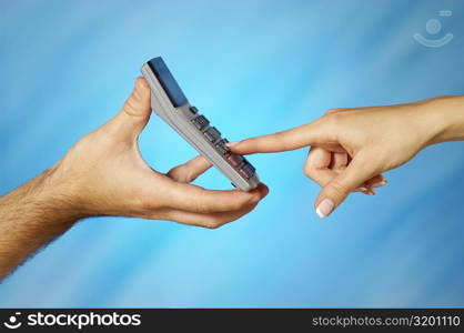 Close-up of a man holding a calculator with a woman&acute;s finger pressing a button