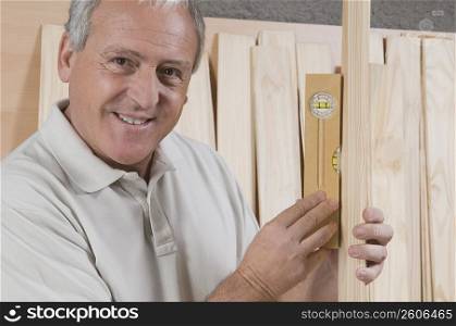 Close-up of a man holding wooden planks and a level