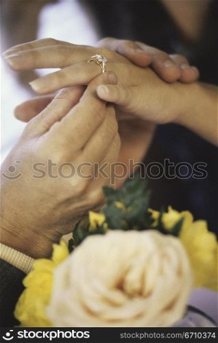Close-up of a man putting a ring on a young woman&acute;s finger