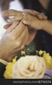 Close-up of a man putting a ring on a young woman&acute;s finger