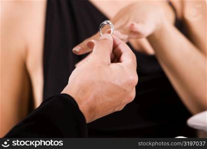 Close-up of a man putting an engagement ring on a young woman&acute;s finger
