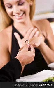Close-up of a man putting an engagement ring on a young woman&acute;s finger