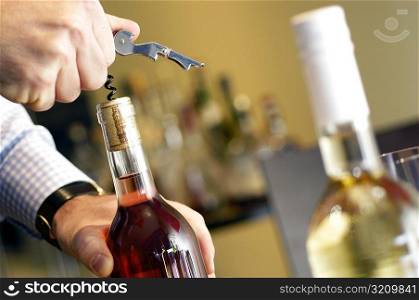 Close-up of a man unscrewing cork of a wine bottle