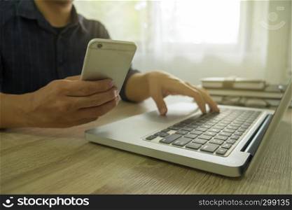 Close up of a man using mobile smart phone and laptop