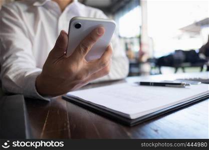 Close up of a man using mobile smart phone on the table.