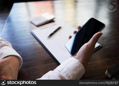 Close up of a man using mobile smart phone on the table.