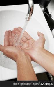 Close-up of a man washing his hands in the bathroom sink