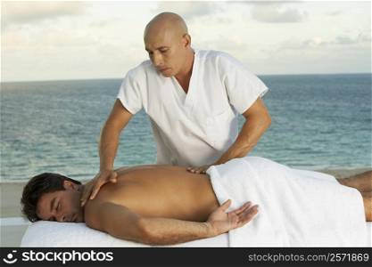 Close-up of a massage therapist giving a young man a back massage