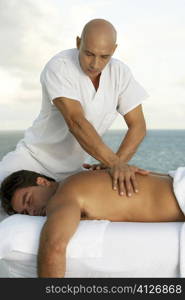 Close-up of a massage therapist giving a young man a back massage