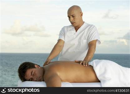 Close-up of a massage therapist giving a young man a back massage
