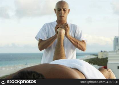 Close-up of a massage therapist giving a young man a foot massage