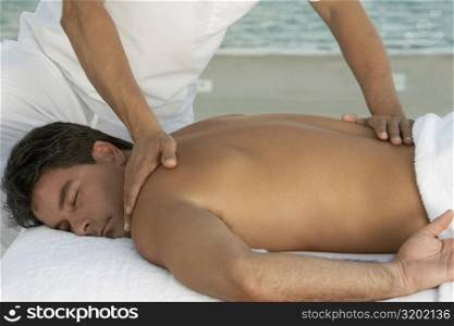 Close-up of a massage therapist massaging a mid adult man&acute;s back