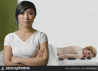 Close-up of a massage therapist with a mature woman lying on a massage table behind her