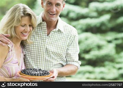 Close-up of a mature couple holding a bowl of blueberries and smiling