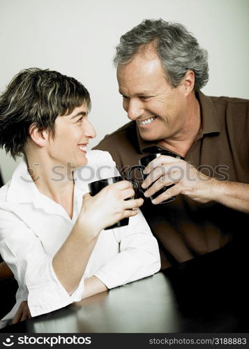 Close-up of a mature couple holding cups of coffee and looking at each other