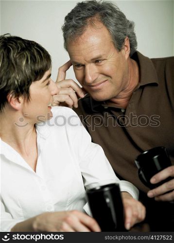 Close-up of a mature couple holding cups of tea and looking at each other